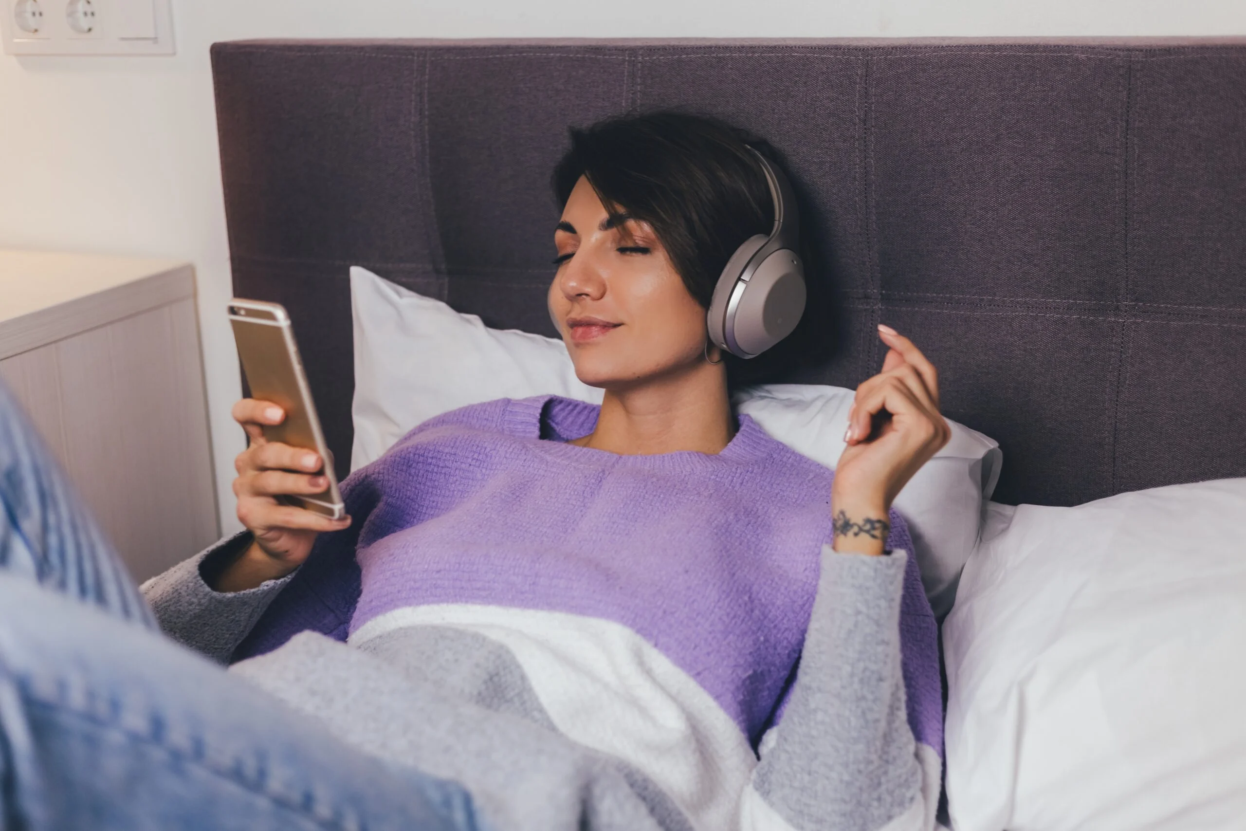 happy woman home comfy bed wearing warm clothes pullover listen music scaled