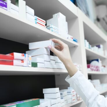 closeup view pharmacist hand taking medicine box from shelf drug store 1