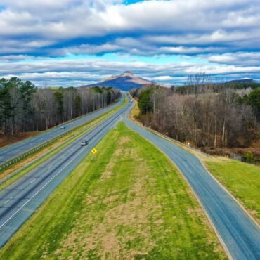 aerial shot road with pilot mountain north carolina usa cloudy blue sky